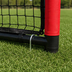 Close‑up detail of metal ground stake securing portable kids soccer goal frame on green grass