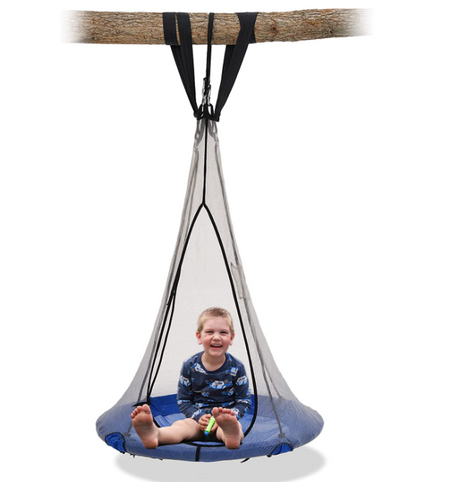 Boy sitting on a saucer round swing hanging on a tree branch